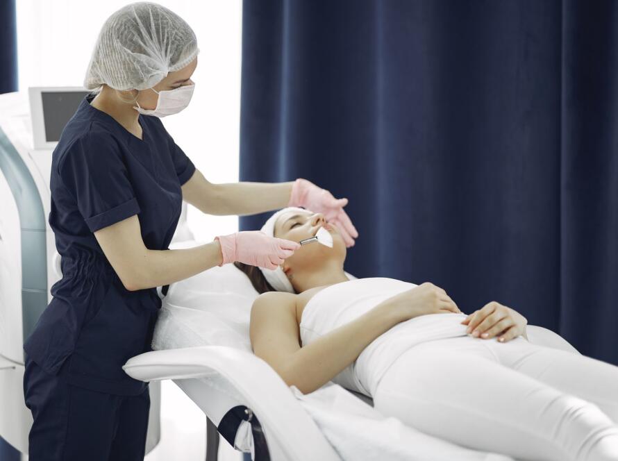 Aesthetician applying facial treatment on a relaxed woman in a modern spa clinic setting, cosmetic clinic brunswick east