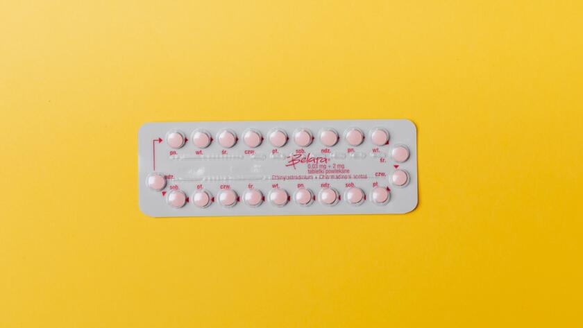 Close-up of a blister pack of pink pills on a vivid yellow background for medication concept.