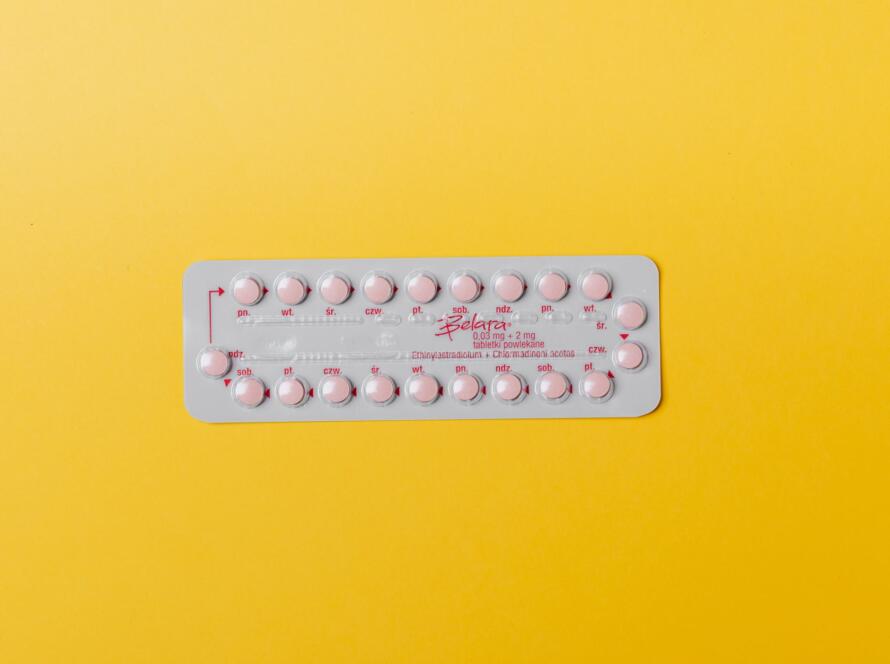 Close-up of a blister pack of pink pills on a vivid yellow background for medication concept.